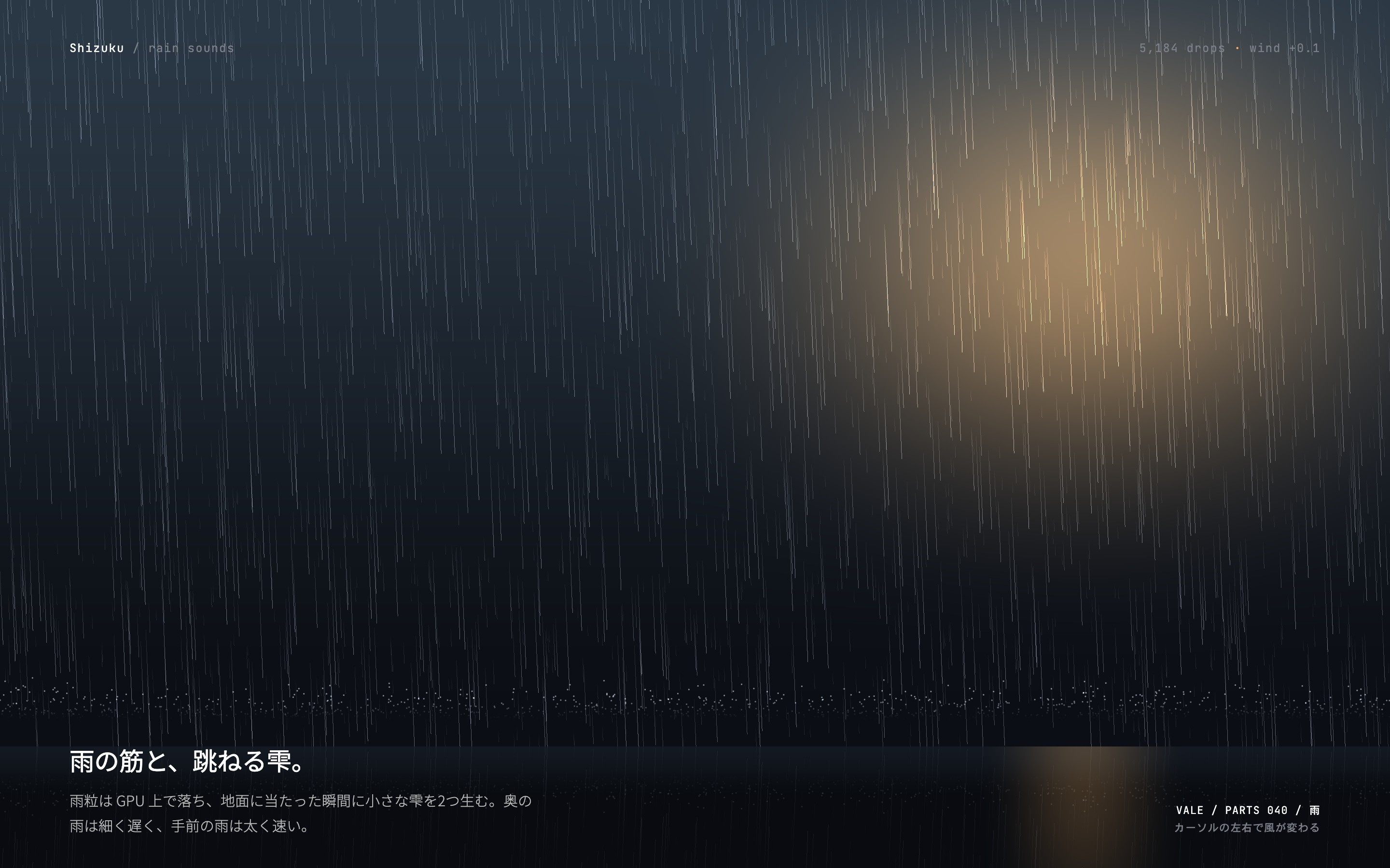 夜の路上に雨の筋が降って地面で跳ね、街灯の近くだけ暖色に光る